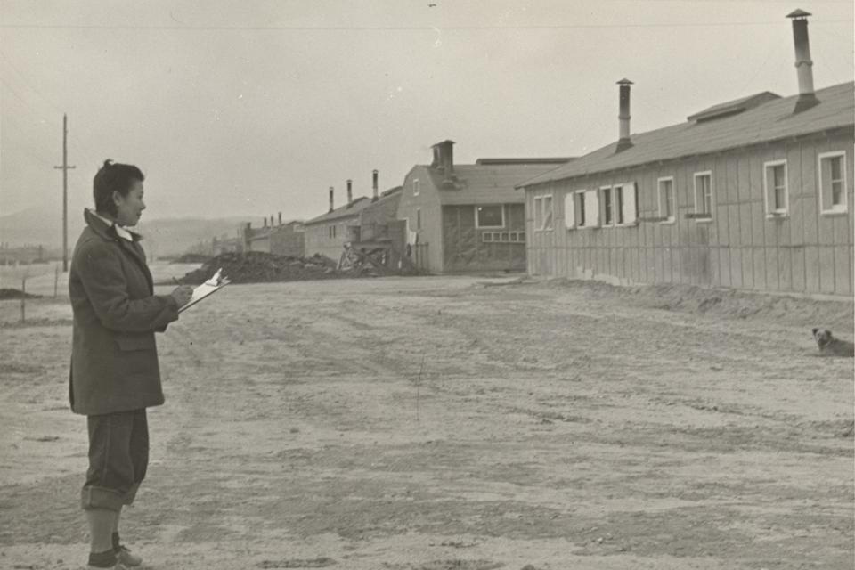 Photo of Miné Okubo sketching in front of barracks